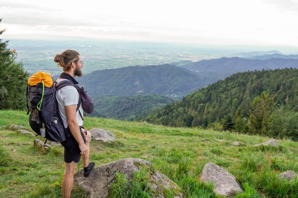 Checkliste Trekking - Wanderer mit Rucksack steht vor Aussicht