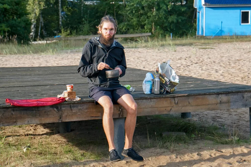 Mann am Frühstücken auf Holzpodest am Strand