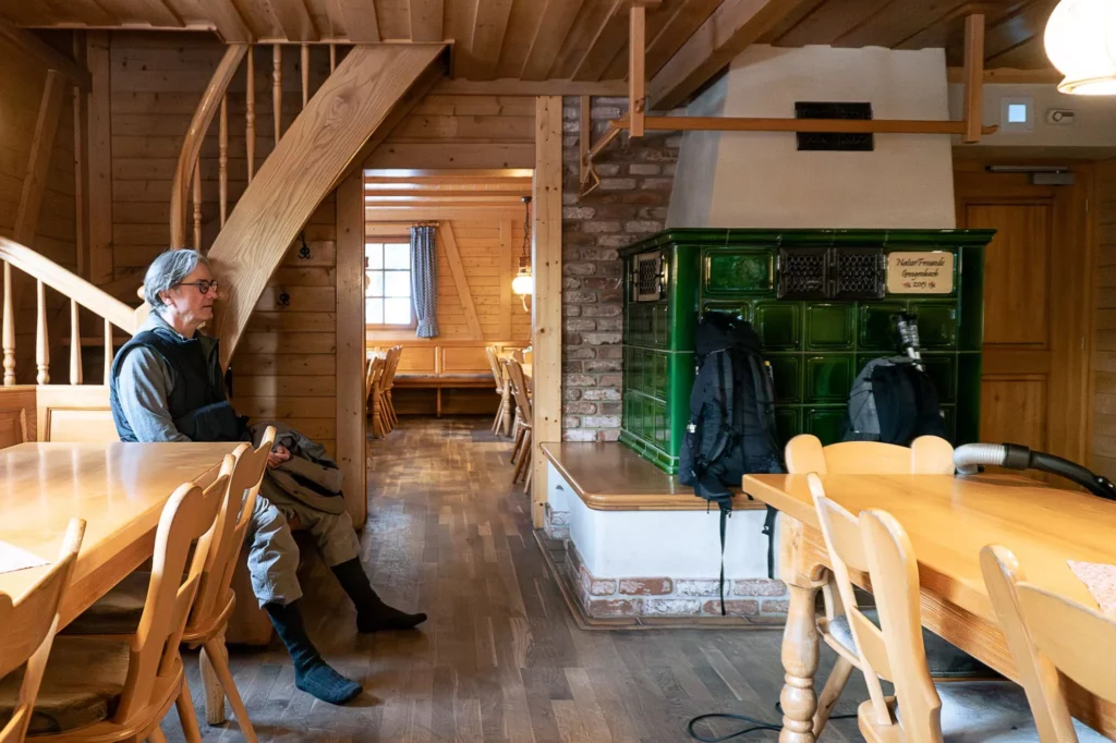 Wanderer sitzt in einem Wohnzimmer mit Kachelofen