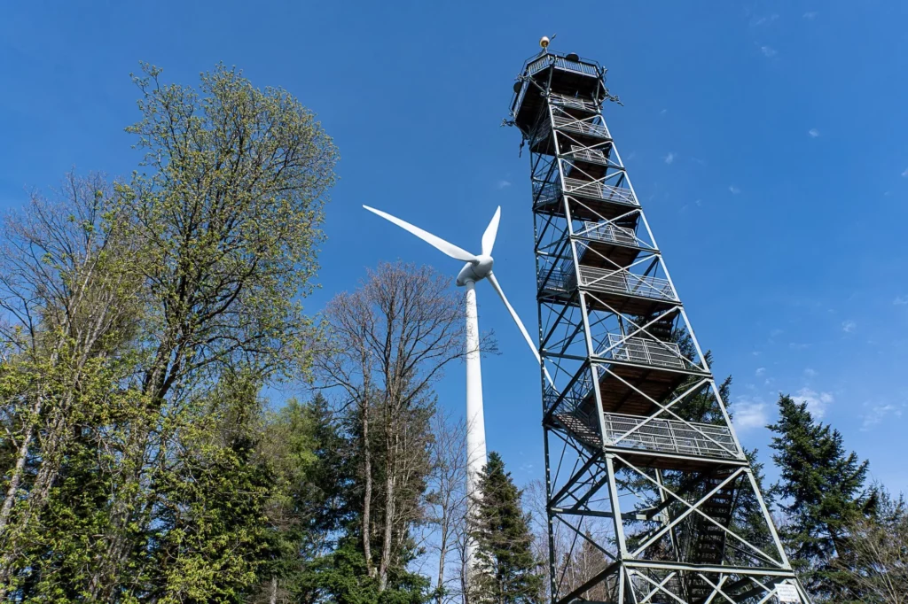 Ein Stahlturm mit Windrad und Bäumen daneben