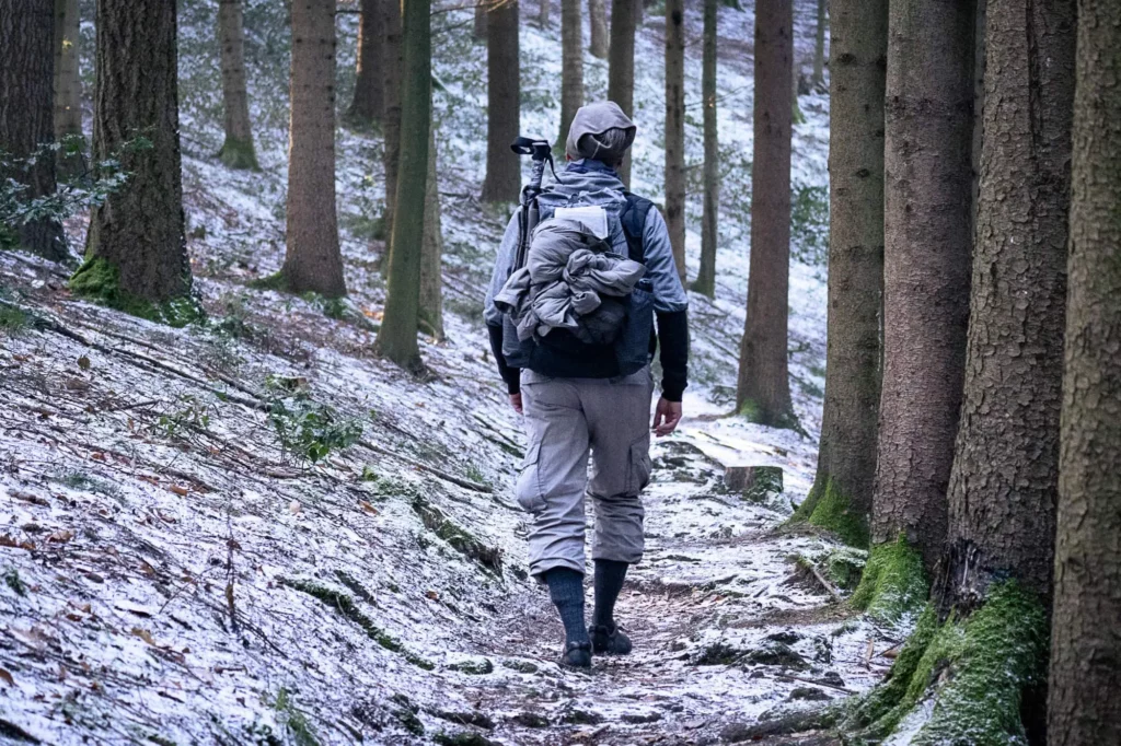 Wanderer geht über Pfad in Wald mit frostigem Boden