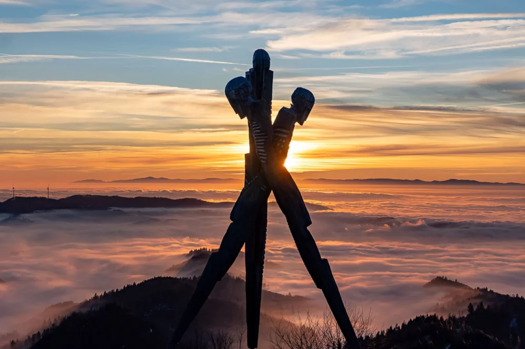Holzdenkmal bei Sonnenuntergang und Nebel