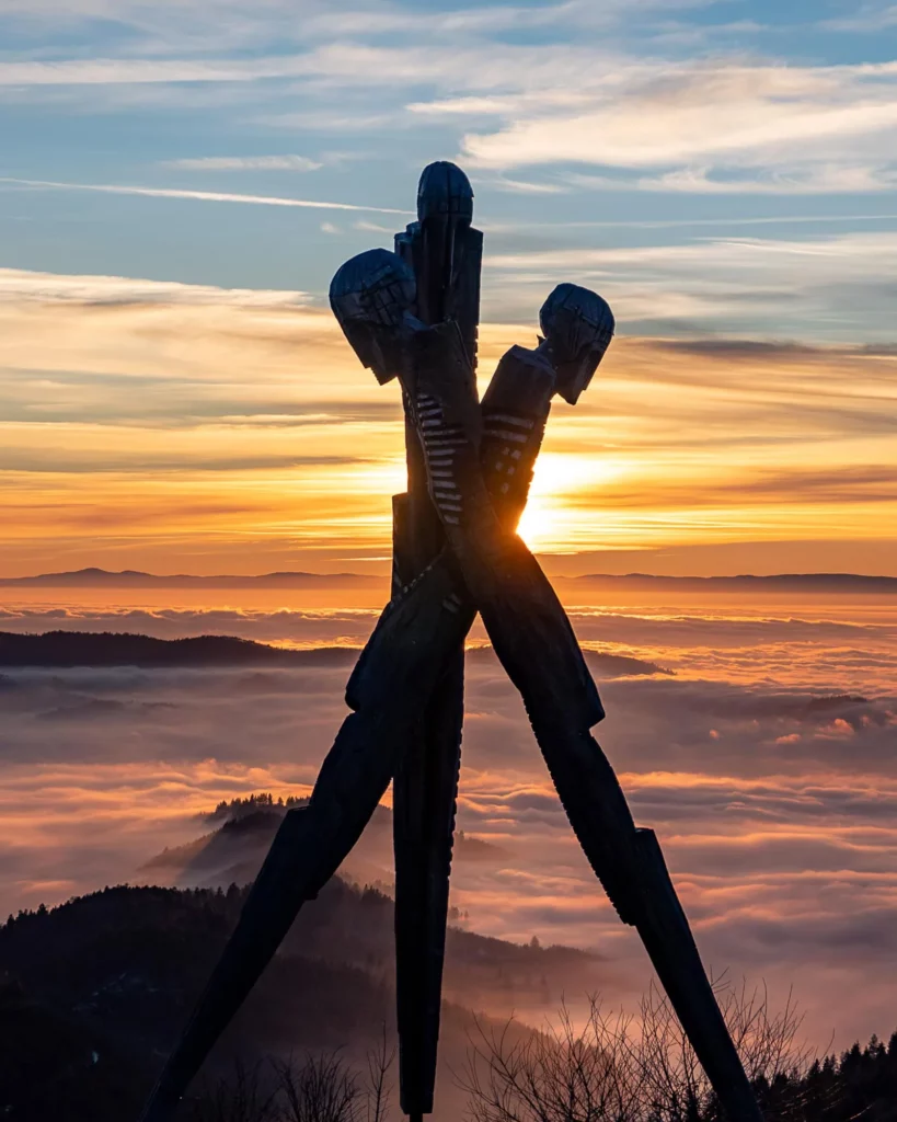Holzdenkmal bei Sonnenuntergang und Nebel