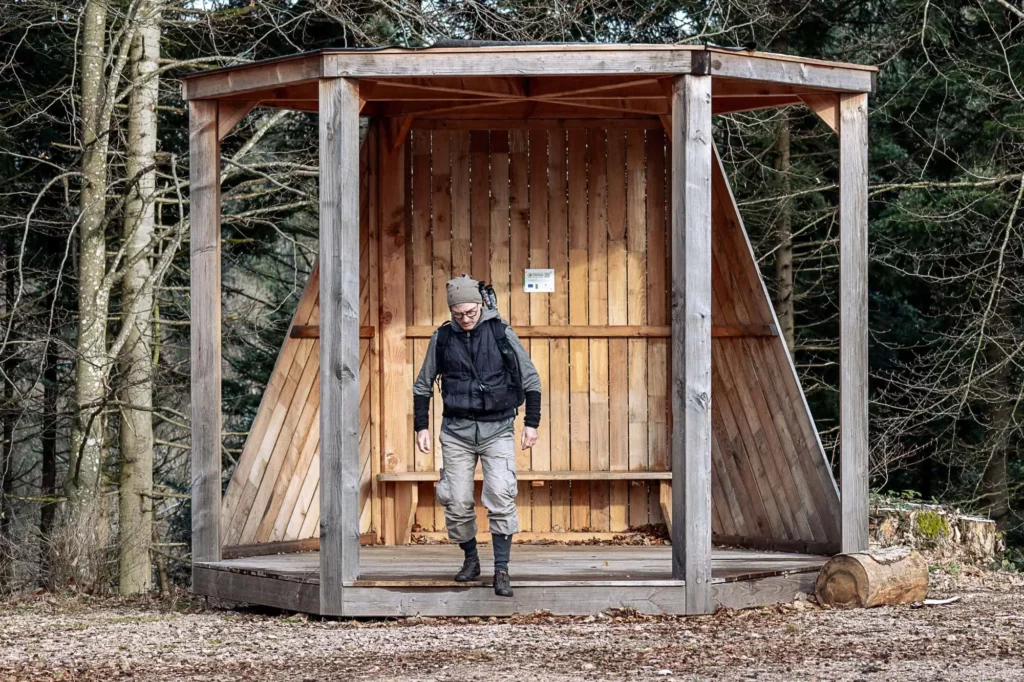 Eine moderne Schutzhütte mit Wanderer davor